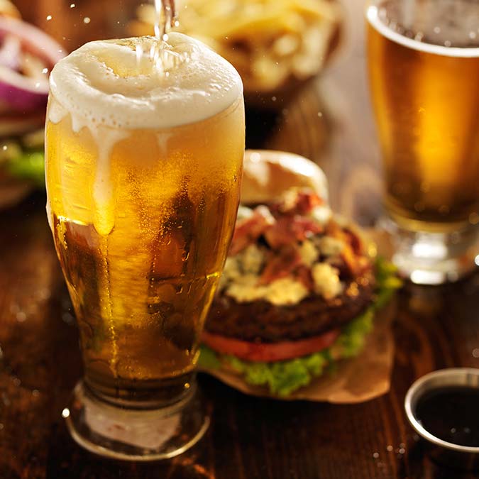 A cold beer is poured by a burger and fries at Sunsets Resort Birchwood WI.