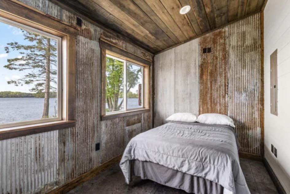 A small rustic bedroom at Sunsets Resort Birchwood WI with corrugated walls and lake views.