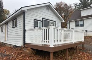 Small white house with a raised porch at Sunsets Resort Birchwood WI, amid autumn leaves.